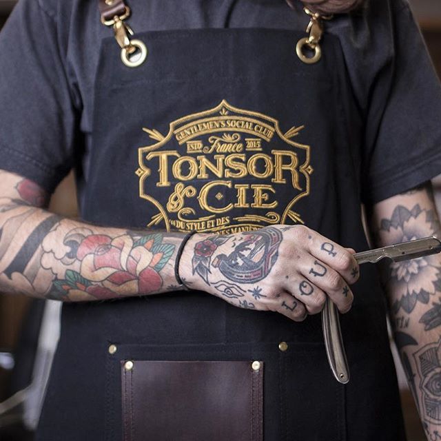 Tablier Tonsor et mains du barbier tenant un rasoir