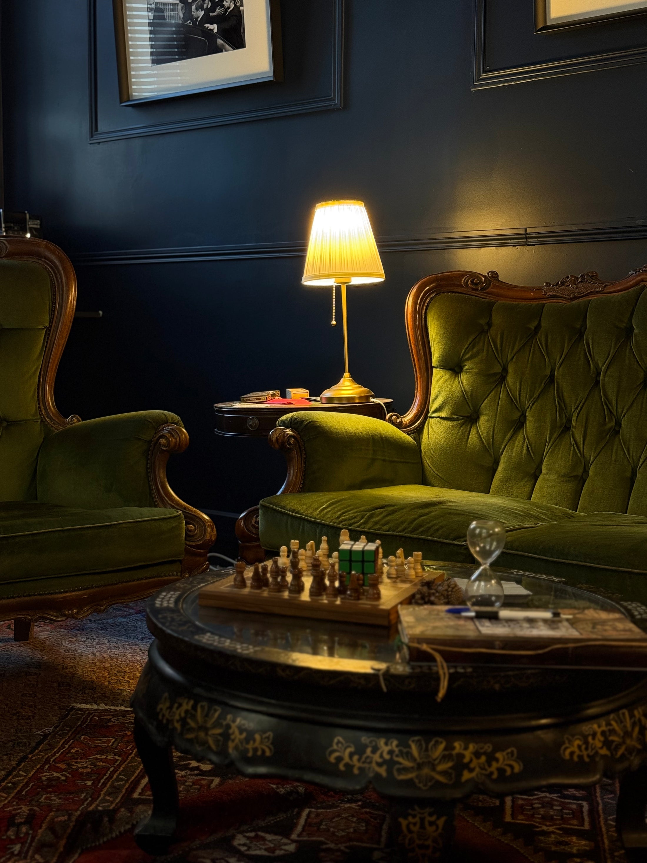 Fauteuils verts, lampe et échiquier autour d’une table ronde