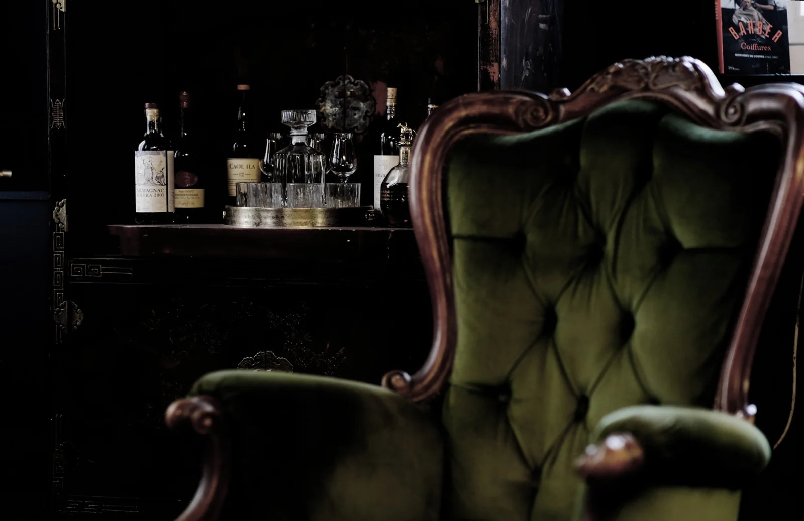 Fauteuil en velours vert et mobilier du Social Club de la Maison Héritage.