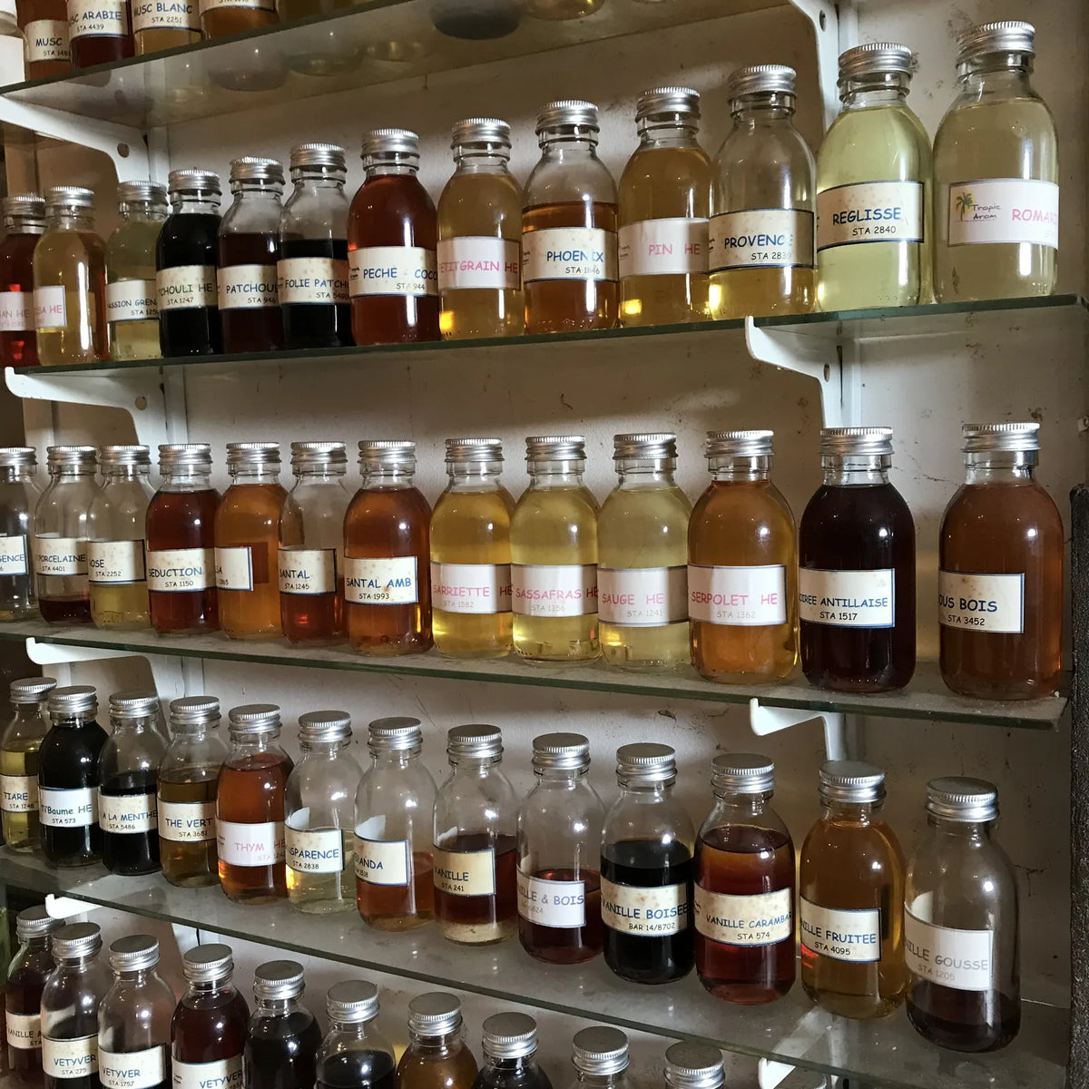 Flacons d’essences et de matières parfumées rangés sur les étagères d’un laboratoire.