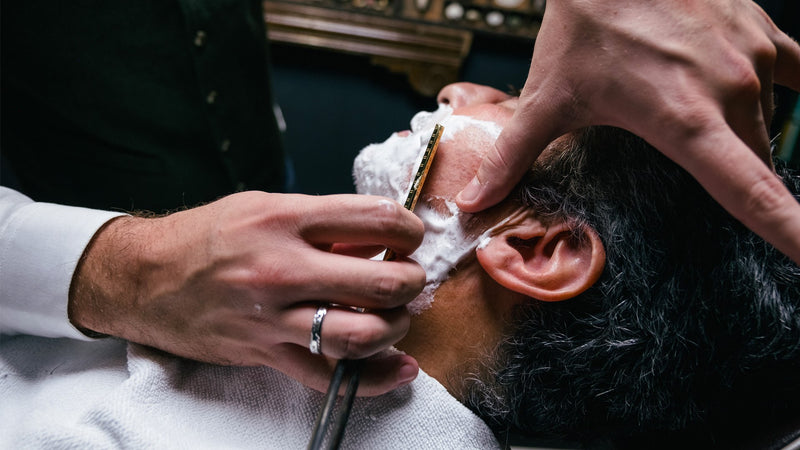 Le geste précis du barbier lors d’un rasage traditionnel.